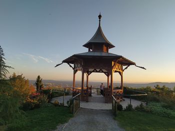 Gazebo by building against sky during sunset