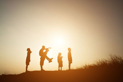 Silhouette people against clear sky during sunset