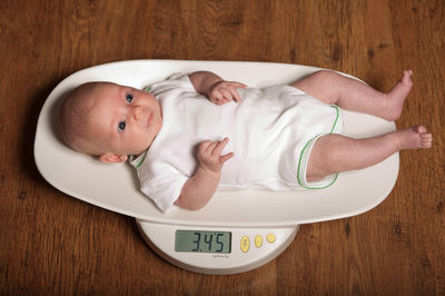 High angle view of baby lying on weight scale