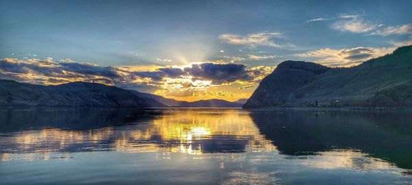 Scenic view of lake by mountains against sky during sunset