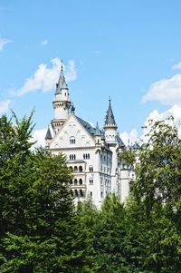 Low angle view of trees and building against sky