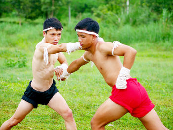 Shirtless young men practicing martial arts on field