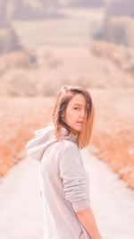 Side view portrait of young woman standing on footpath