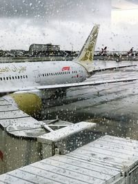 Airplane seen through wet glass during rainy season