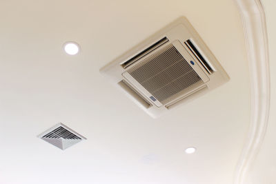 Low angle view of electric lamp and air conditioner hanging on ceiling