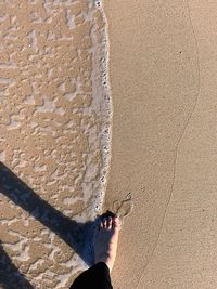 Low section of person standing on sand at beach
