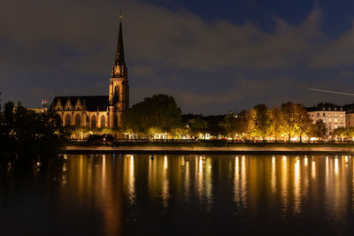 Reflection of illuminated building in water against sky