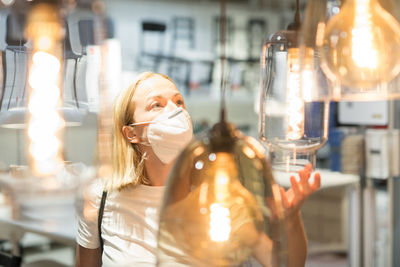 Side view of woman wearing mask standing at store