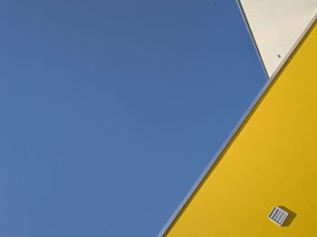 Low angle view of yellow sign against clear sky