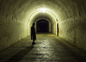 Rear view of silhouette man walking in tunnel