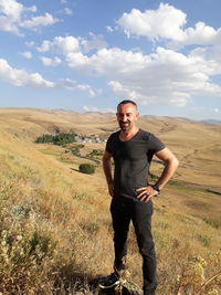 Portrait of man smiling while standing on landscape against sky