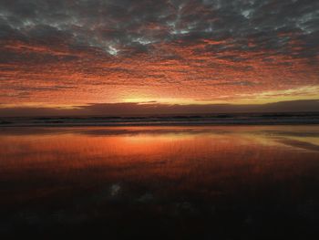 Scenic view of sea against dramatic sky during sunset