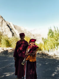 Rear view of people standing on road against sky