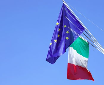 Low angle view of flags against clear blue sky