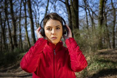 Young woman with short hair is listening to the music while she walks in the park.