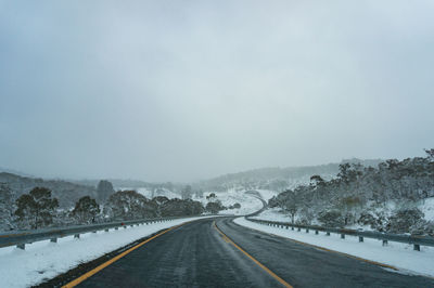 Road leading towards snow covered mountain against sky