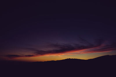 Silhouette landscape against dramatic sky during sunset
