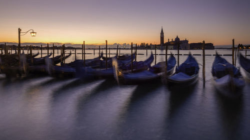 View of boats moored in canal at sunset