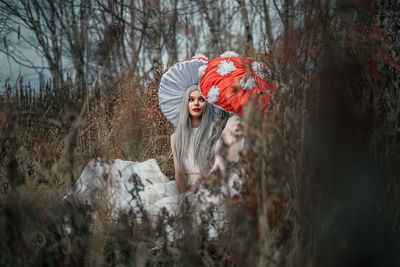 Woman standing by trees in forest during winter