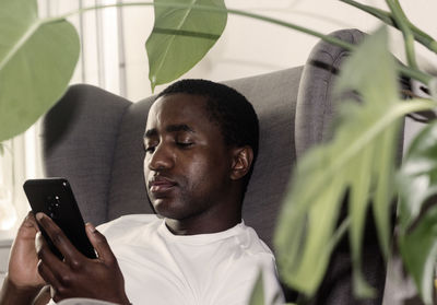 Man using smart phone while sitting on armchair