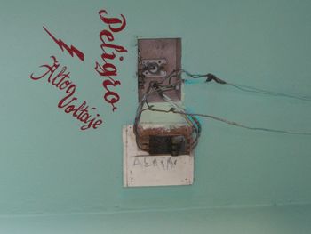 Damaged fuse box and warning sign on wall