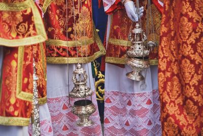 Midsection of priests holding censer during procession