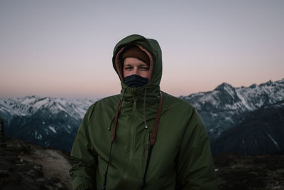 Portrait of man standing against mountain during winter