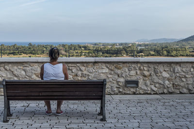 Rear view of woman sitting on bench