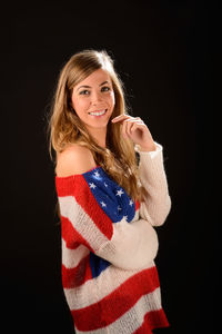 Portrait of happy mid adult woman standing against black background