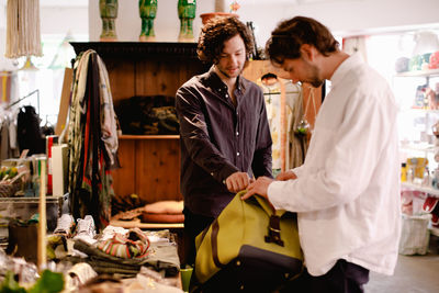 Salesman showing luggage bag to customer at store