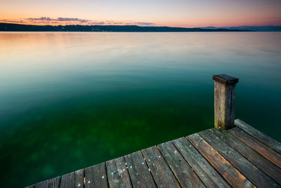 Pier on lake against sky during sunset