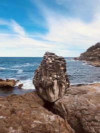 Rock formation on beach against sky