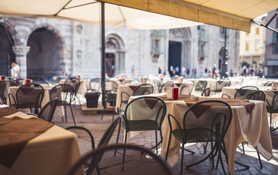 Empty chairs and tables at sidewalk cafe against buildings