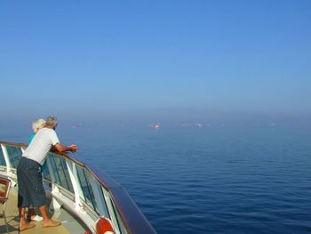 Rear view of man looking at sea against blue sky