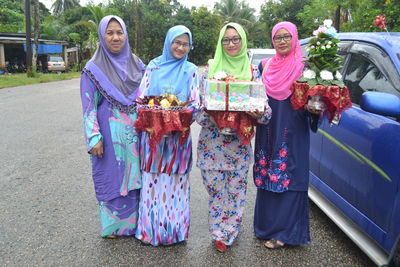 Portrait of happy women wearing traditional clothing while standing by car