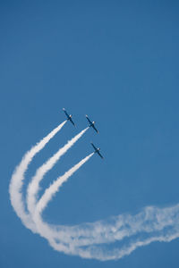 Low angle view of airplane flying against blue sky