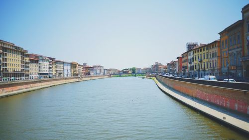 Canal in city against clear sky