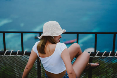 Rear view of woman sitting against sea