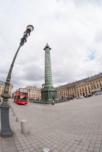 Low angle view of statue in city against cloudy sky