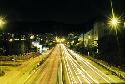 Light trails on road along illuminated street lights at night