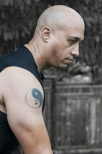 Side view of shaved head man with yin yang symbol tattoo