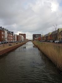 Canal amidst buildings in city against sky