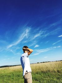 Man standing on cliff in grassy field against sky