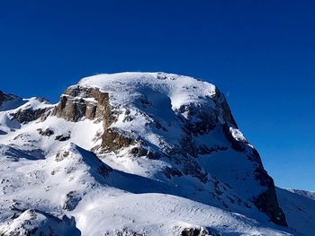 Snow covered mountain against blue sky