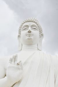 Low angle view of statue of buddha against cloudy sky