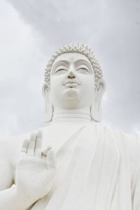 Low angle view of statue of buddha against cloudy sky