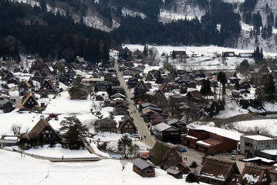 High angle view of snow covered houses and trees in city