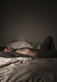 Adult man in open shirt and jeans lying on bed