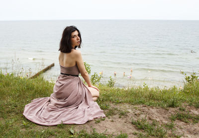 Young woman at beach against sky