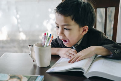 Portrait of boy with open book on table